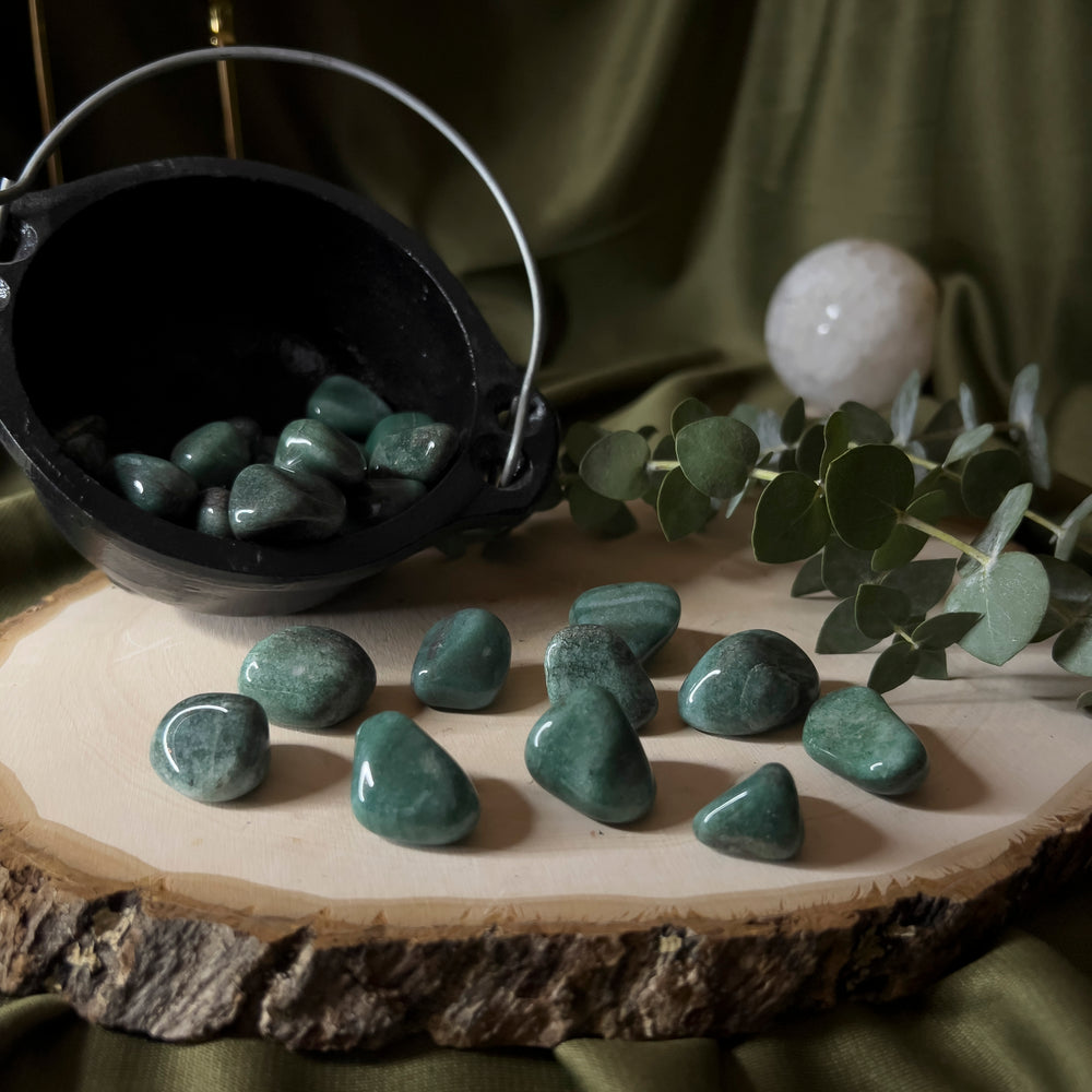 Multiple Deep Green Aventurine Tumbles on wood slice display.