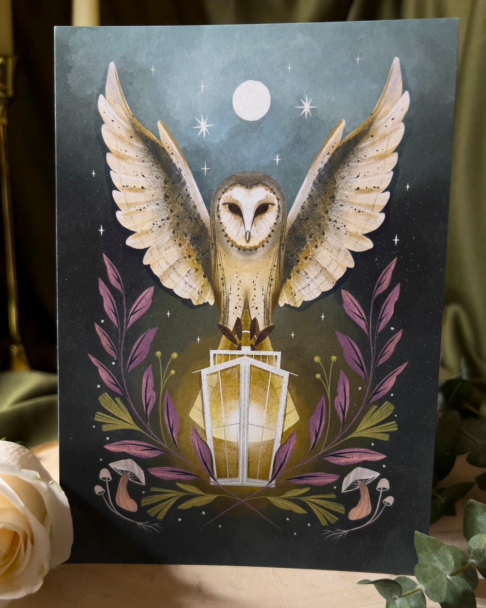 An art print depicting an owl carrying a lantern through the night with the moon above.