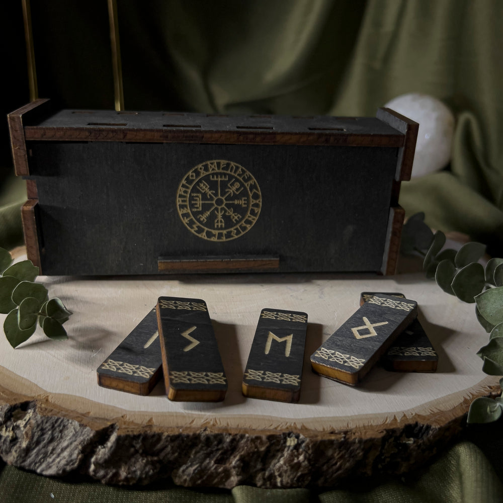 Black wood box with the vegvisir in the center, small wood rune staves lay in front of it, individually carved.