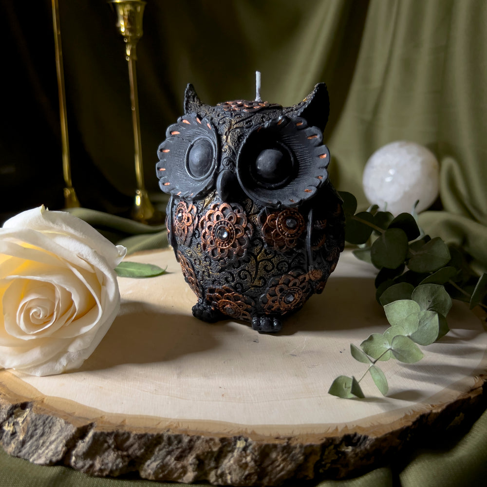 Black owl statue candle with gold floral designs and decorated with rhinestones.