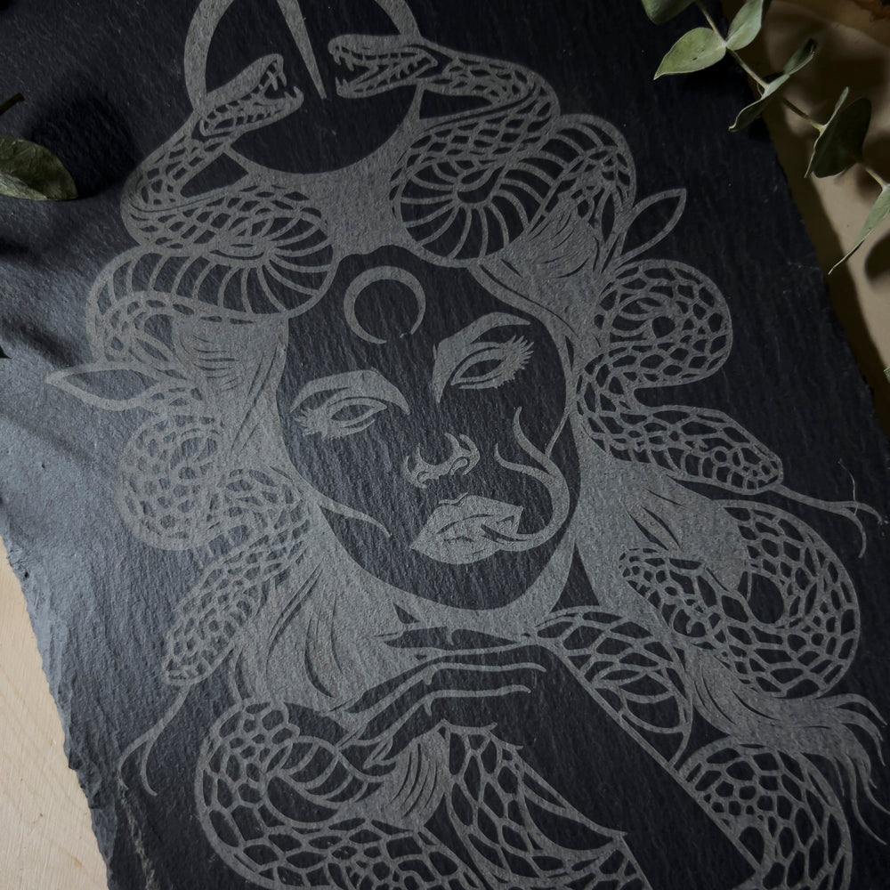 Slate wall art depicting Medusa with snakes all around her.