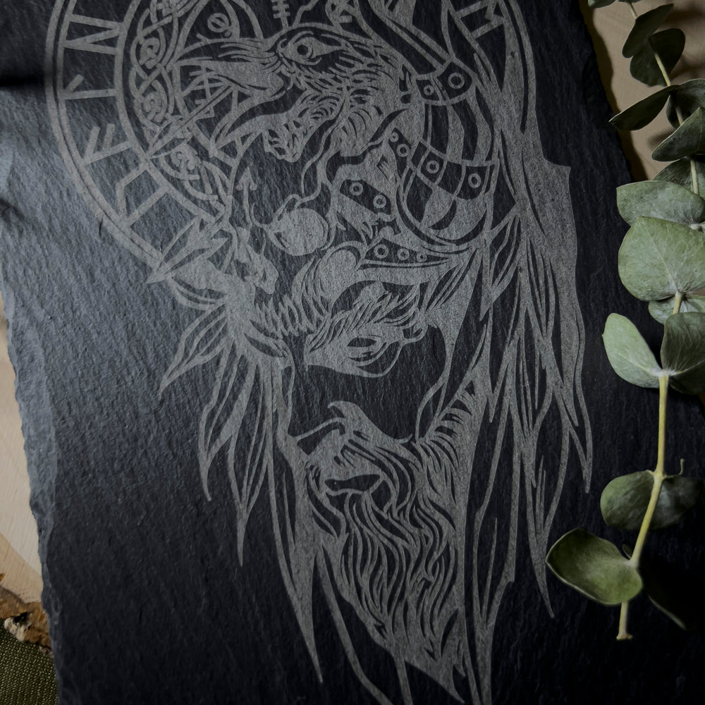 A slate wall art depicting Odin's face with a raven behind him and a skull on his head.