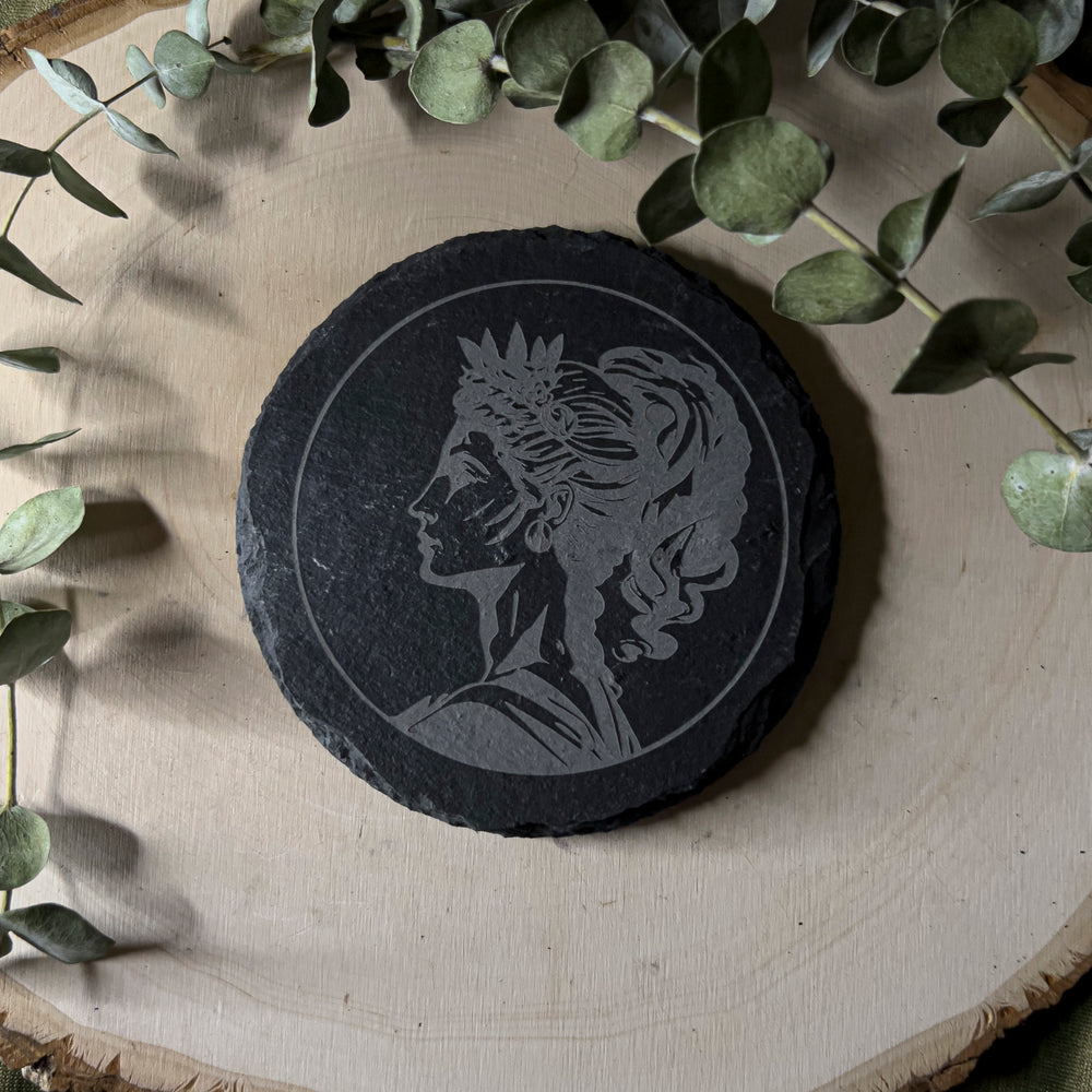 Round slate tile with a carved depiction of Hera, close up.