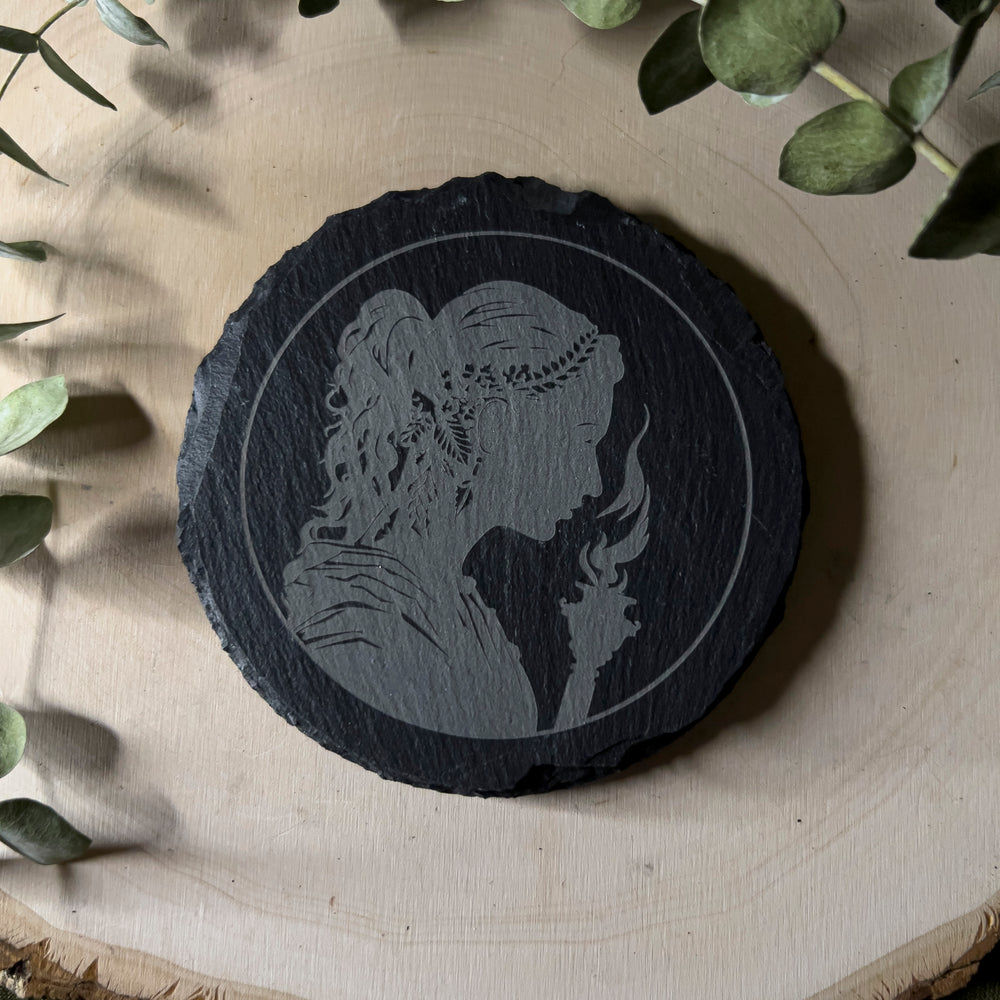 Round slate tile with a carved depiction of Hekate, close up.