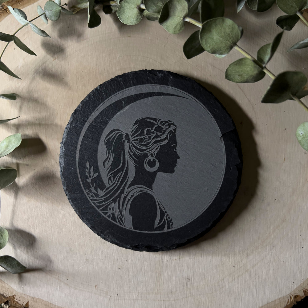 Round slate tile with a carved depiction of Artemis, close up.