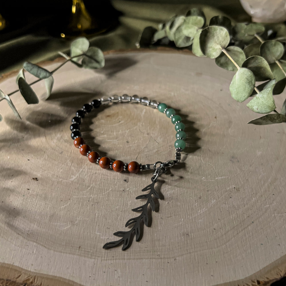 A bracelet with gemstone beads in the colors of the Palestinian flag with an olive branch charm. 
